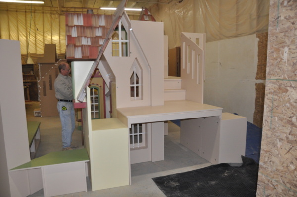 Indoor village playhouse for a waiting room with bookshelf, benches and storage space.